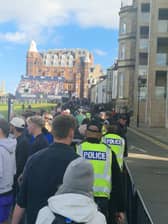 Police officers walk up the 18th hole at St Andrews as Dermot Desmond plays