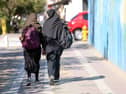 Iranian students, carrying their school backpacks, walk along a street during the first day of school year in Tehran