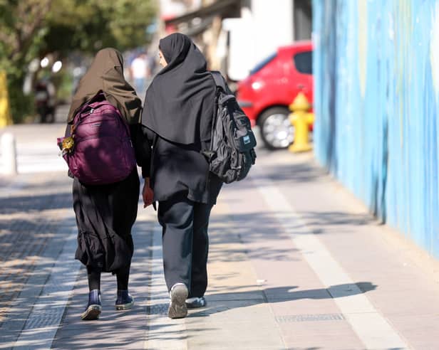Iranian students, carrying their school backpacks, walk along a street during the first day of school year in Tehran