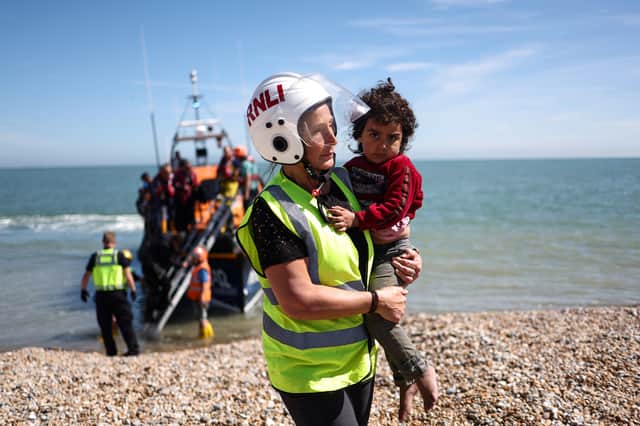 A member of the Royal National Lifeboat Institution carries a child as migrants, picked up at sea attempting to cross the English Channel from France, are helped ashore at Dungeness on the southeast coast of England. Picture: Henry Nicholls