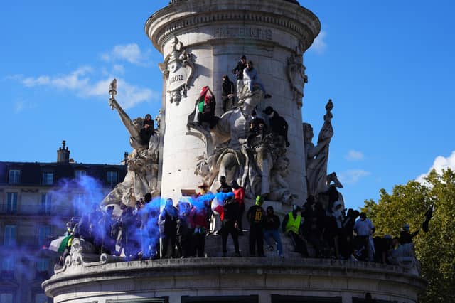 Protesters climb onto the Monument à la Republique