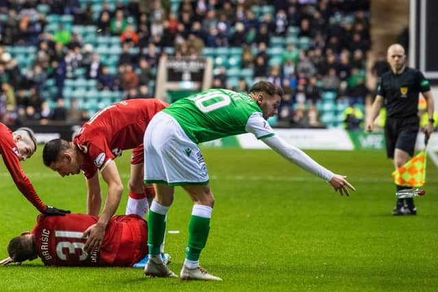 Martin Boyle removes the vodka bottle from the pitch as Rangers defender Borna Barisic lies injured on the surface. Picture: SNS