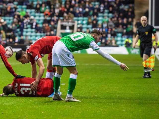 Martin Boyle removes the vodka bottle from the pitch as Rangers defender Borna Barisic lies injured on the surface. Picture: SNS