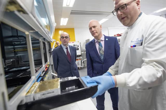 Scotland's Public Health Minister Joe FitzPatrick (centre) and Professor Rory Gunson (left) look on as clinical support technician Douglas Condie (right) extracts viruses from swab samples. Picture: PA
