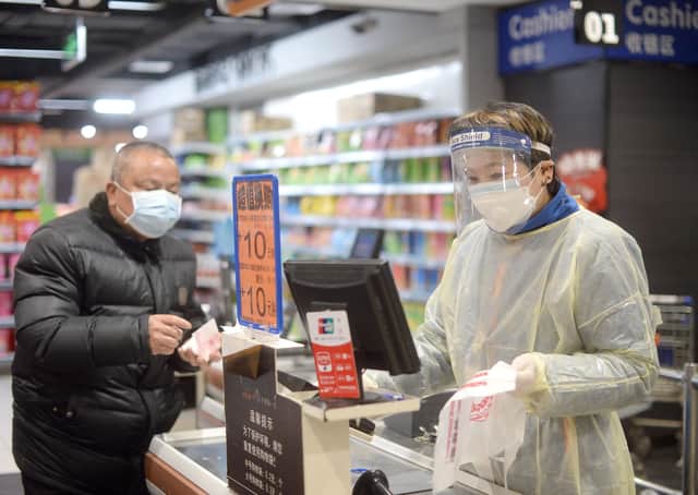 A staff member wearing a protective mask and suit works at a supermarket in Wuhan, the epicentre of the outbreak of a novel coronavirus, in China's central Hubei province (Picture: STR/AFP via Getty Images)