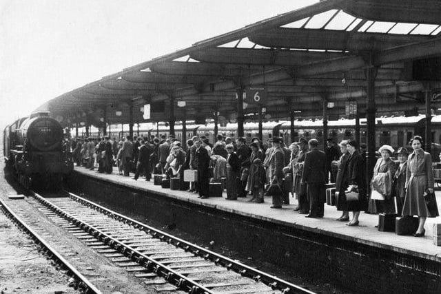 Passengers line a platform at Leeds Station as a train approaches from Glasgow for London in May 1955.