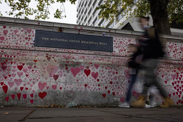 Members of the public walk past the Covid Memorial Wall.