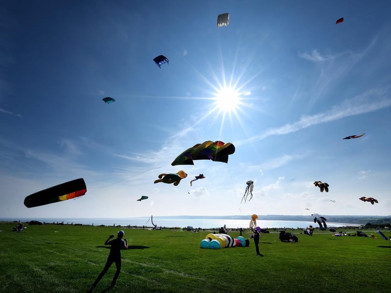 Bright blue skies filled with kites looking out to sea.