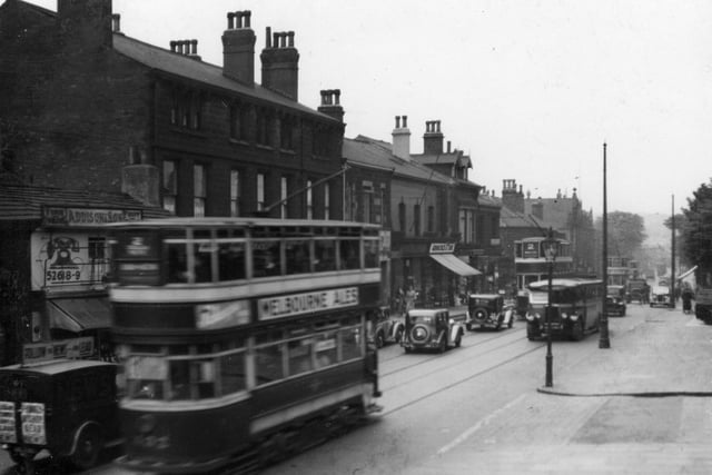 A stretch of Otley Road, looking towards North Lane in June 1937. On the left, with telephone sign on wall is the fish shop of William Addison. Further to the right, shop with blind down is at number 31, Groocock and Son, grocers.