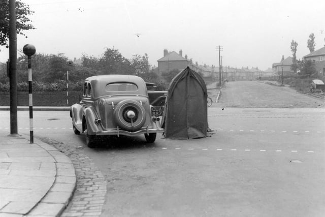 A car at the junction of Shaw Lane with Otley Road in July 1936. There is a telephone repair shelter in the road. Belisha beacons can be seen on the left. St Anne's Road is in the background.