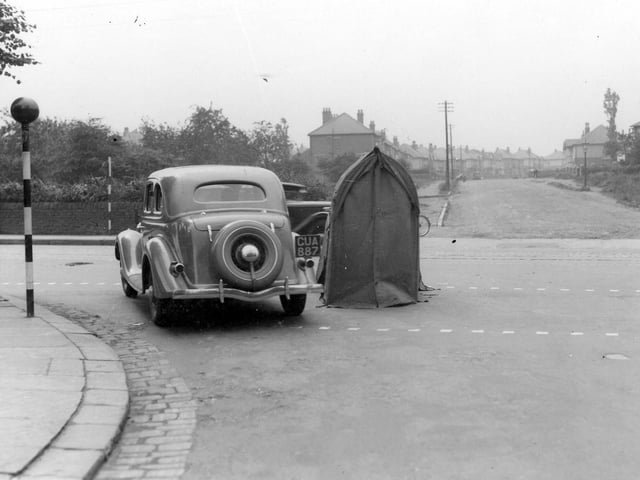 A car at the junction of Shaw Lane with Otley Road in July 1936. There is a telephone repair shelter in the road. Belisha beacons can be seen on the left. St Anne's Road is in the background.