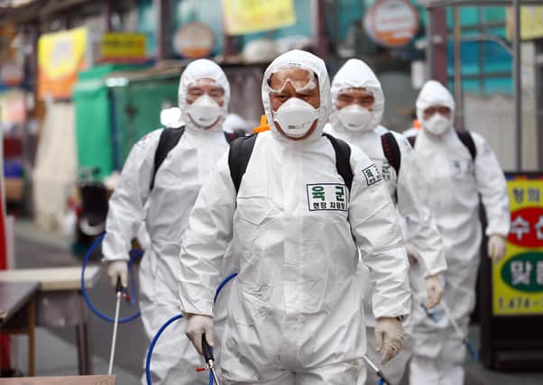 South Korean soldiers wearing protective clothing spray disinfectant as part of preventive measures against the spread of the Covid-19 coronavirus at a market in Daegu (Picture: Yonhap/AFP via Getty Images)