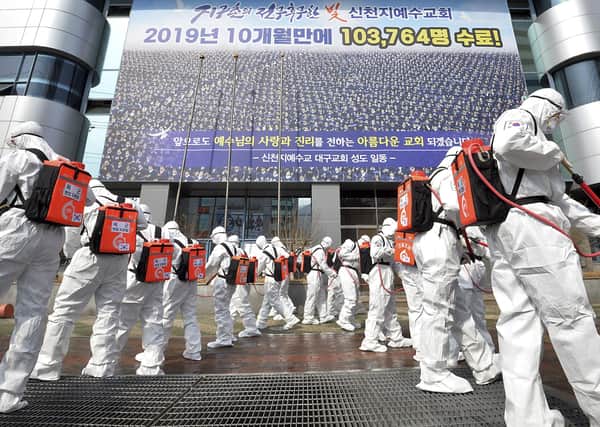Soldiers wearing protective suits spray disinfectant to prevent the spread of the coronavirus in front of a church in Daegu, South Korea (Picture: Lee Moo-ryul/Newsis via AP)