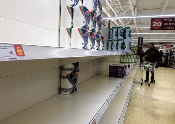 The shelves of a supermarket in Edinburgh emptied of toilet rolls by anxious shoppers