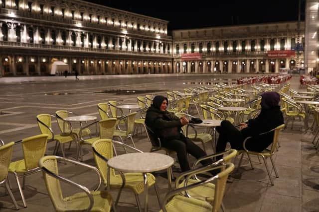 Two tourists talk to each other in a deserted Venice square. (Photo: Getty)