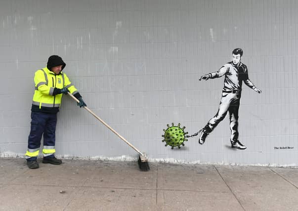 A key worker walks past a mural by The Rebel Bear on Bath St, Glasgow. Picture: John Devlin
