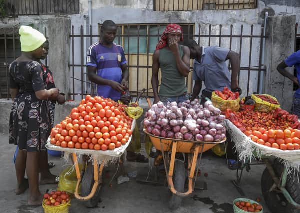 A woman buys tomatoes and onions from street sellers in Lagos, Nigeria, amid fears over food supplies (Picture: Sunday Alamba/AP)