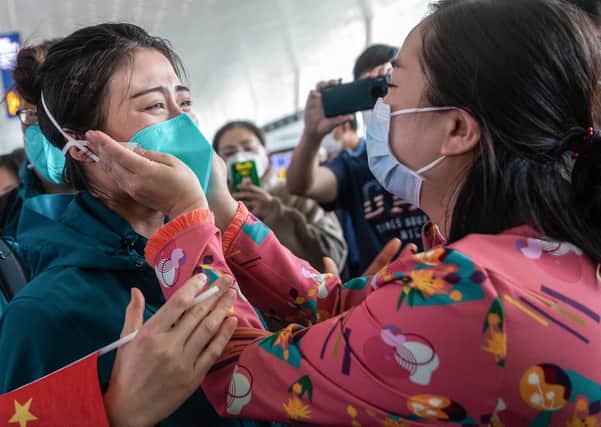 A medical staff member from Peking Union Medical College Hospital, left, tears up as she prepares to leave Wuhan, but was China's government slow to act over the virus? (Picture: STR/AFP via Getty Images)