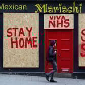 A person passes a boarded up restaurant in Edinburgh which has been painted with an NHS supporting message. Picture: PA
