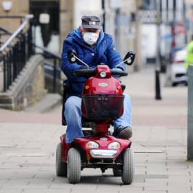 A man drives a mobility scooter while wearing a face mask through Falkirk