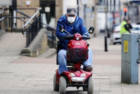 A man drives a mobility scooter while wearing a face mask through Falkirk