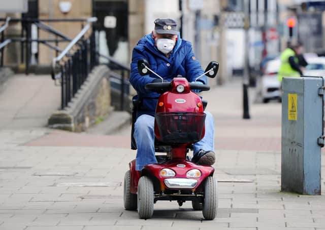 A man drives a mobility scooter while wearing a face mask through Falkirk