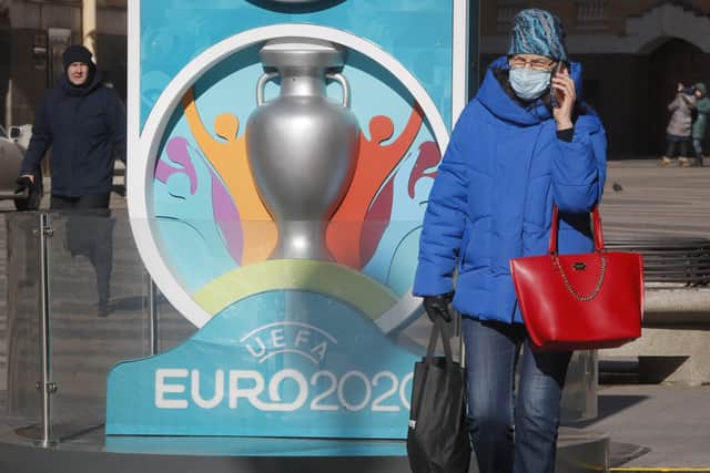 A woman wearing a medical mask walks past a sign with Euro 2020 emblem in St.Petersburg, one of the host cities. Picture: Dmitri Lovetsky/AP