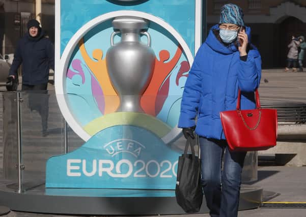 A woman wearing a medical mask walks past a sign with Euro 2020 emblem in St.Petersburg, one of the host cities. Picture: Dmitri Lovetsky/AP