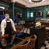A waiter wearing a protective face mask poses in the nearly empty restaurant "Le Lyrique cafe brasserie", in Geneva. Picture: Getty