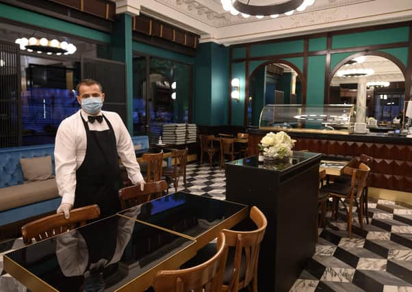 A waiter wearing a protective face mask poses in the nearly empty restaurant "Le Lyrique cafe brasserie", in Geneva. Picture: Getty