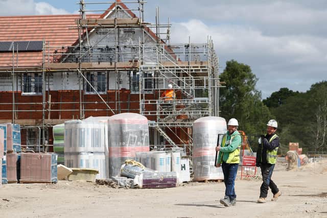 Workers carry a pane of glass on a construction site near Guildford, south-west of London. Picture: Adrian Dennis/AFP via Getty Images