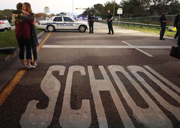 Two people embrace at a police check point near the Marjory Stoneman Douglas High School in Parkland, Florida, where 17 people were killed by a gunman in February 2018. The lockdown has resulted in a rare shootings-free month for schools in the US (Picture: Mark Wilson/Getty Images)