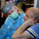 A nurse in PPE speaks to a care home resident (Picture: Frank Augstein/AP)