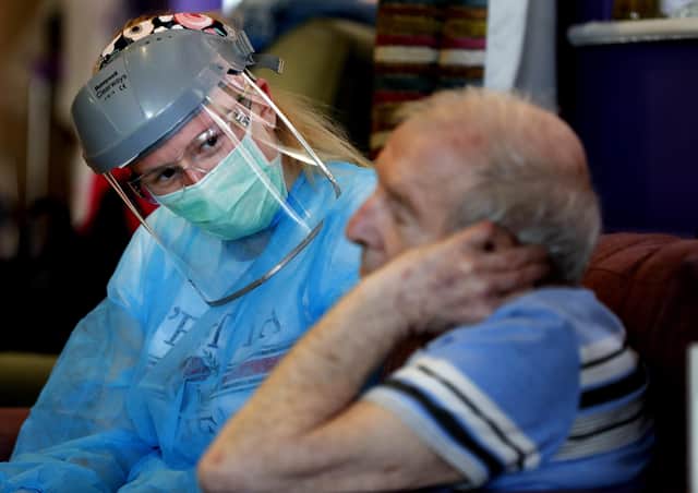 A nurse in PPE speaks to a care home resident (Picture: Frank Augstein/AP)