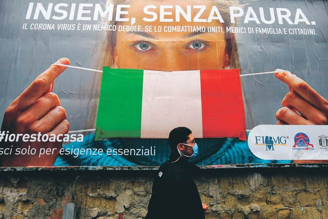 A man walks past a large billboard raising awareness to the measures taken by the Italian government to fight against the spread of Covid-19. The UK has officialy passed Italy to now have Europe's highest death toll from coronavirus. Picture: Carlo Hermann/AFP via Getty Images