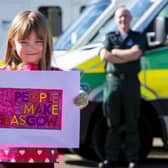Scarlett Shaw (6) hands her customised People Make Glasgow poster to ambulance driver John Connolly at the Springburn Ambulance Centre, for display in the depot’s window. Picture: Ross MacDonald