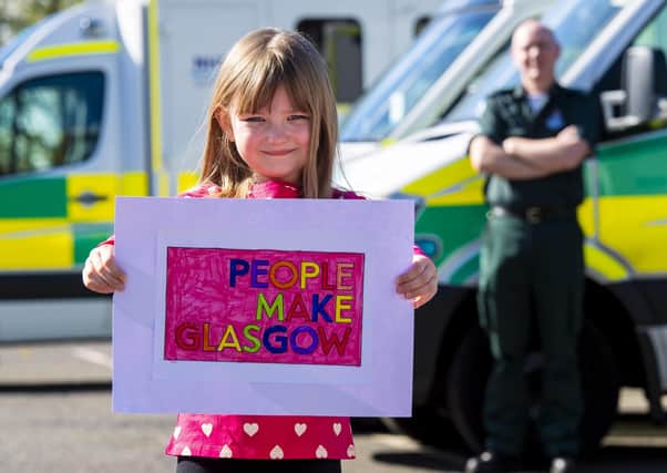 Scarlett Shaw (6) hands her customised People Make Glasgow poster to ambulance driver John Connolly at the Springburn Ambulance Centre, for display in the depot’s window. Picture: Ross MacDonald