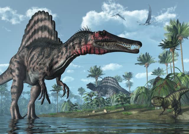 A tropical prehistoric scene with several dinosaurs, including two spinosauruses, a psittacosaurus and two dorygnathuses in flight
