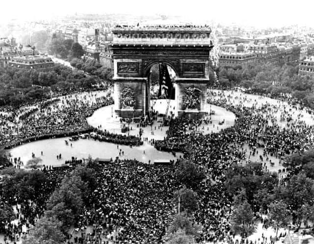 Thousands of people flock to the Arc de Triomphe in Paris to celebrate the Allies’ Victory in, not ‘over’, Europe (Picture: AP)