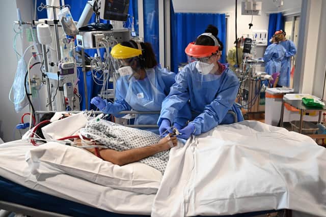 Clinical staff wear personal protective equipment (PPE) as they care for a patient at an intensive care unit. Picture : Neil Hall/PA Wire