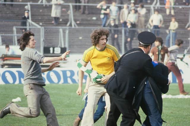 A Celtic fan charges on to the pitch as police officers try to restore order at Hampden