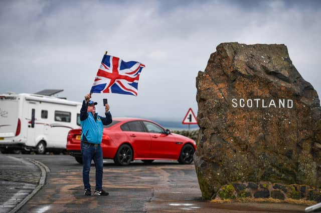 A man flies a Union flag at the top of Redesdale on the A68 at the border between Scotland and England (Picture: Jeff J Mitchell/Getty Images)
