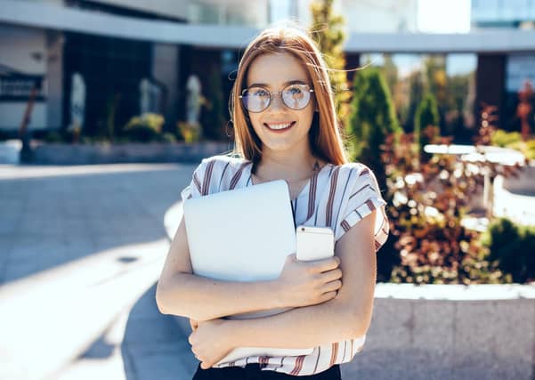 Lovely caucasian woman with red hair and freckles posing with a computer and phone in front of sunshine