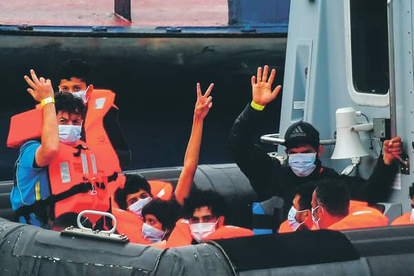 Migrants gesture as they arrive in port aboard a Border Force vessel after being intercepted while crossing the English Channel from France. Picture: Peter Summers/Getty Images
