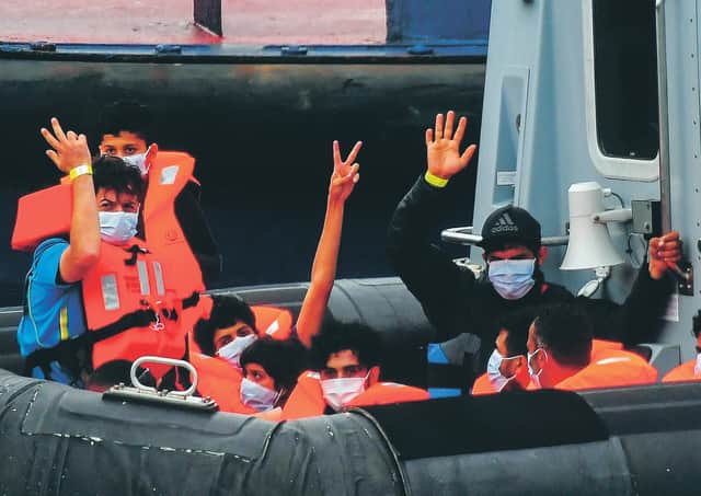 Migrants gesture as they arrive in port aboard a Border Force vessel after being intercepted while crossing the English Channel from France. Picture: Peter Summers/Getty Images