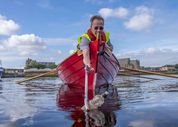 A volunteer fishes a bottle out of the River Clyde as part of Keep Scotland Beautiful's Upstream Battle clean-up campaign