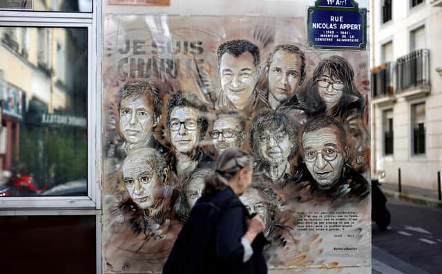 A woman walks past a painting by French street artist and painter Christian Guemy, known as C215, in tribute to members of Charlie Hebdo newspaper who were killed by Islamist extremist gunmen in January 2015 (Picture: Thomas Coex/AFP via Getty Images)
