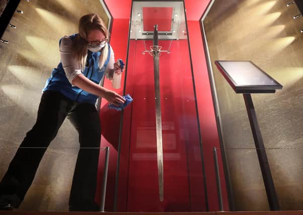 Sally Jeffrey visitor attraction assistant at the Wallace Monument cleans the case which houses the William Wallace sword in the Hall of Arms room at the monument