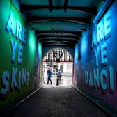 Members of the public walk past graffiti in Glasgow. East Dunbartonshire and Renfrewshire have joined Glasgow city, West Dunbartonshire and East Renfrewshire, with  people banned from visiting other households. Picture: Photo by Jeff J Mitchell/Getty Images