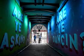 Members of the public walk past graffiti in Glasgow. East Dunbartonshire and Renfrewshire have joined Glasgow city, West Dunbartonshire and East Renfrewshire, with  people banned from visiting other households. Picture: Photo by Jeff J Mitchell/Getty Images